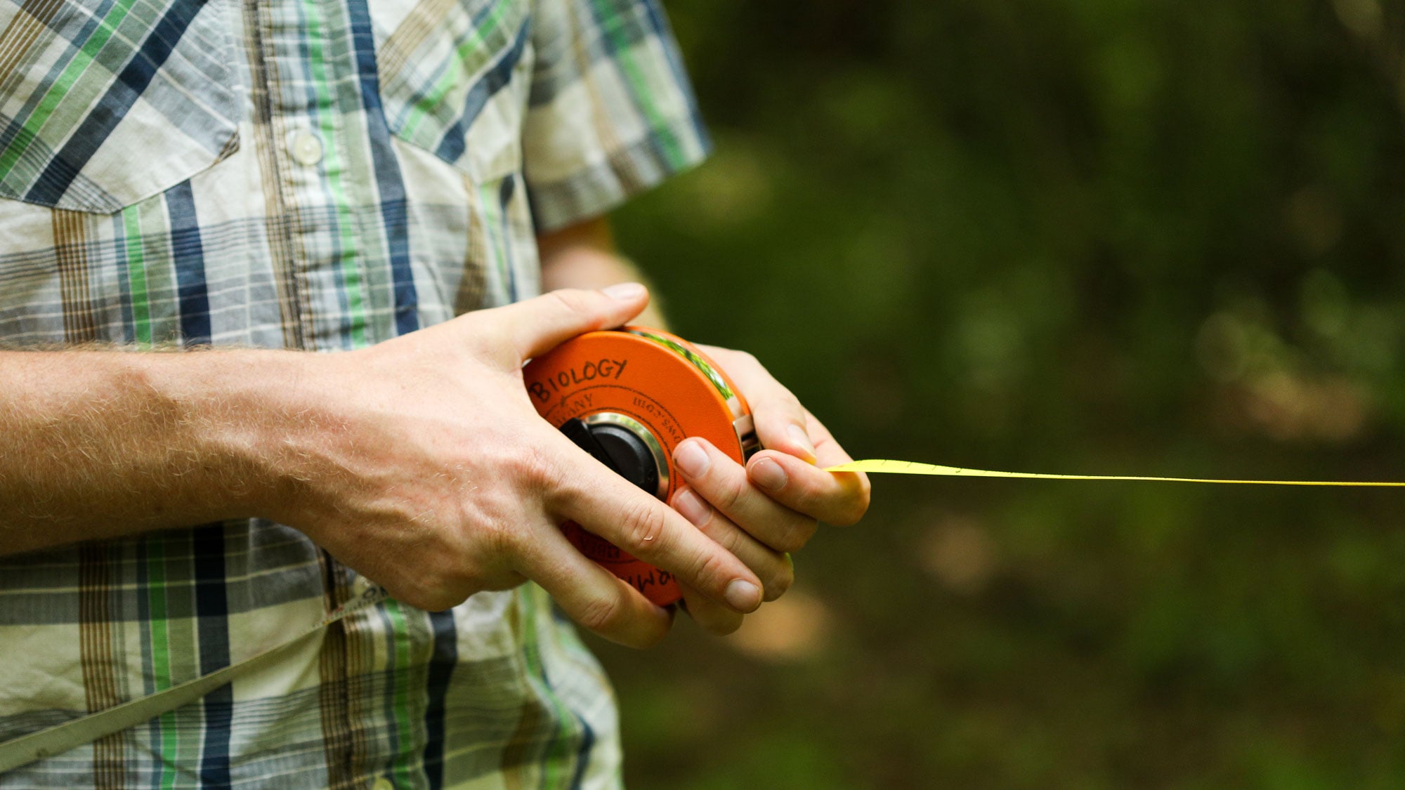 Professor holding a measuring tape with Biology written on it