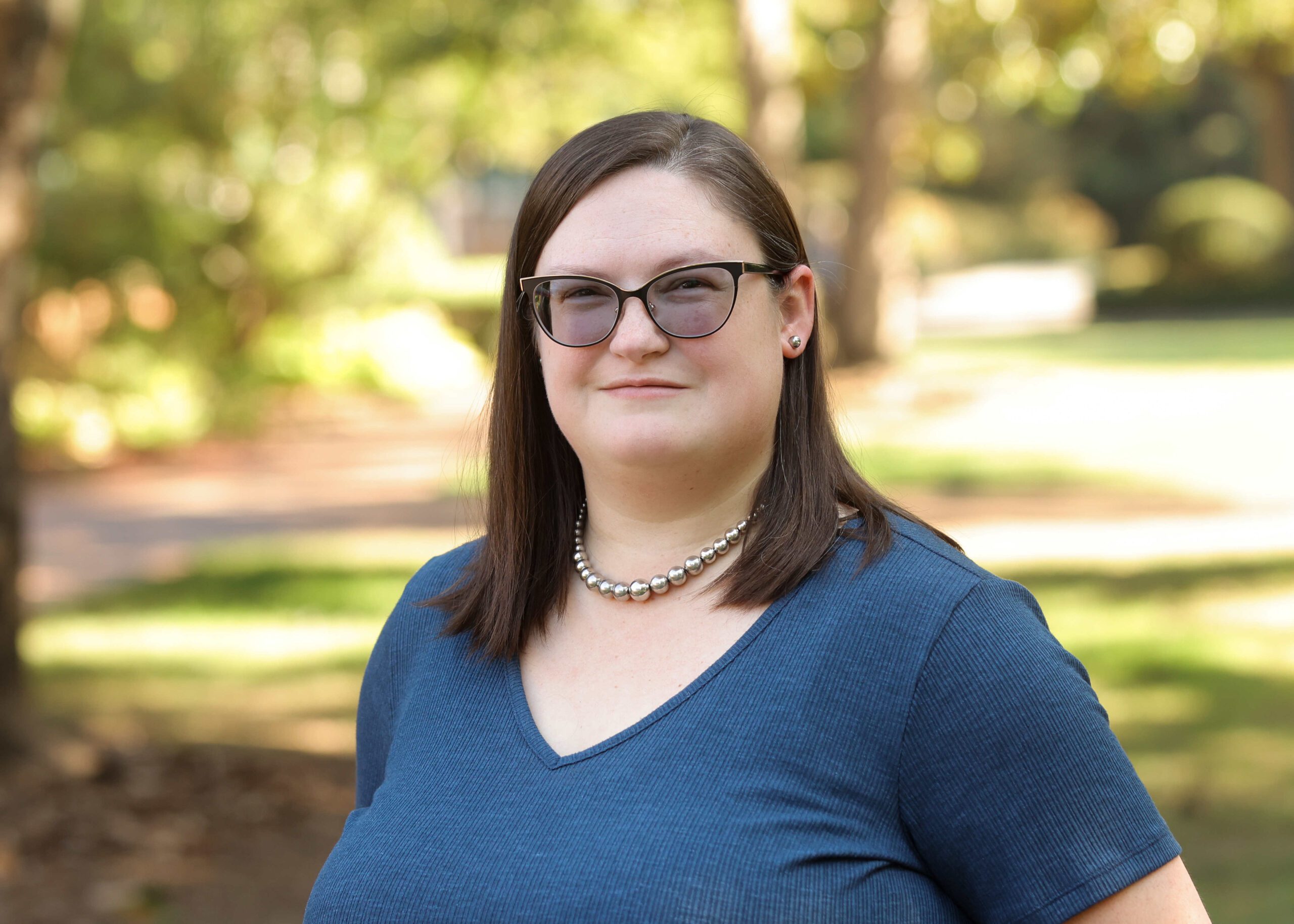 A white woman with glasses and shoulder length dark brown hair