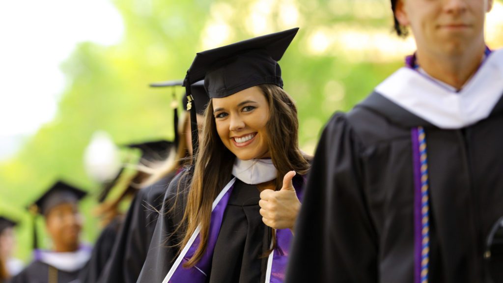 Student giving a thumbs up while in line during commencement