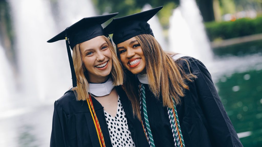 Students smiling in front of fountain after graduation