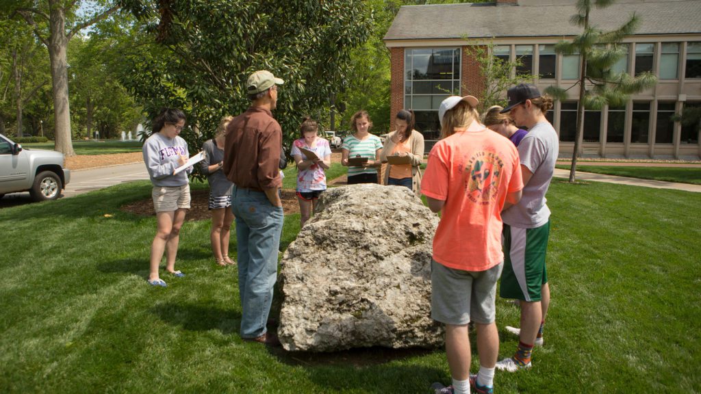 Students standing around rock outside polymer