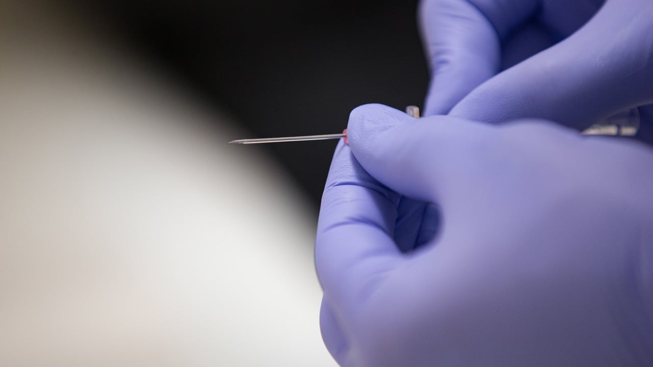 student with gloves holding a syringe
