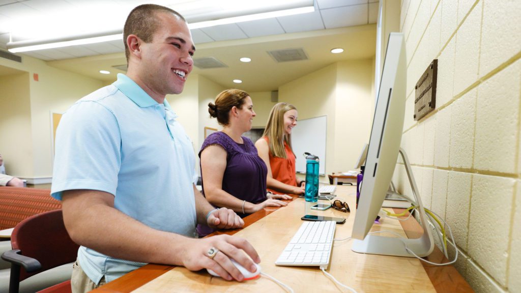 Student smiling while using desktop