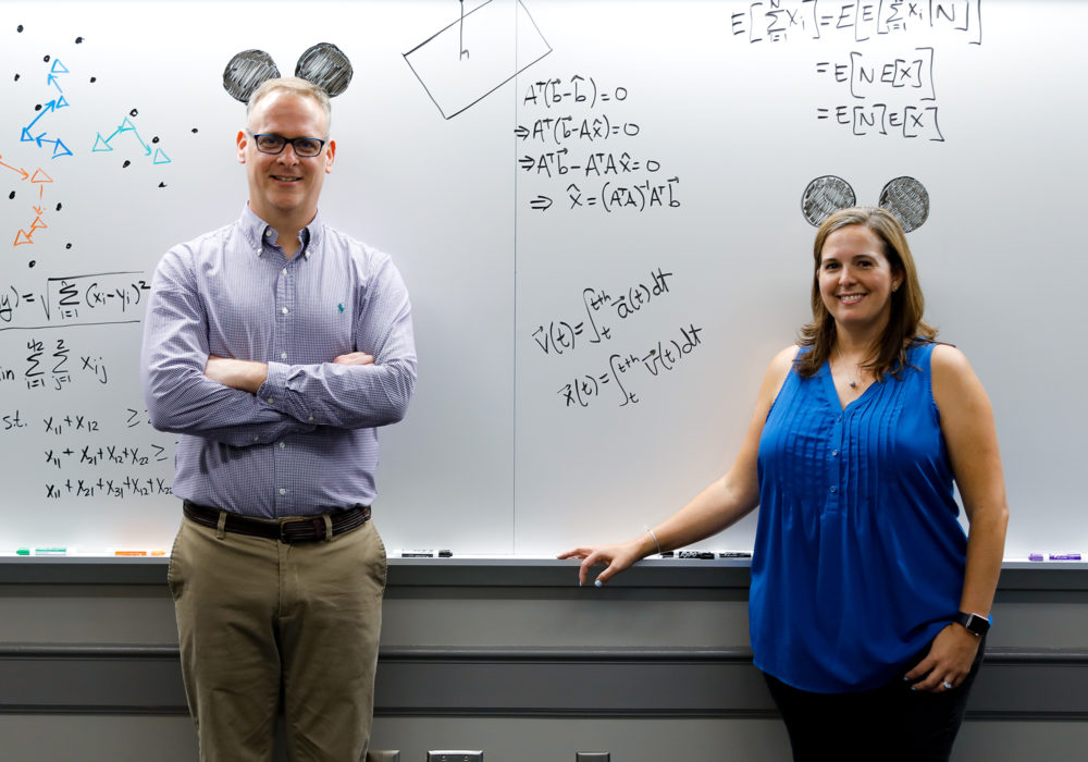 Dr. Hutson and Dr. Bouzarth with Disney-related math on a whiteboard