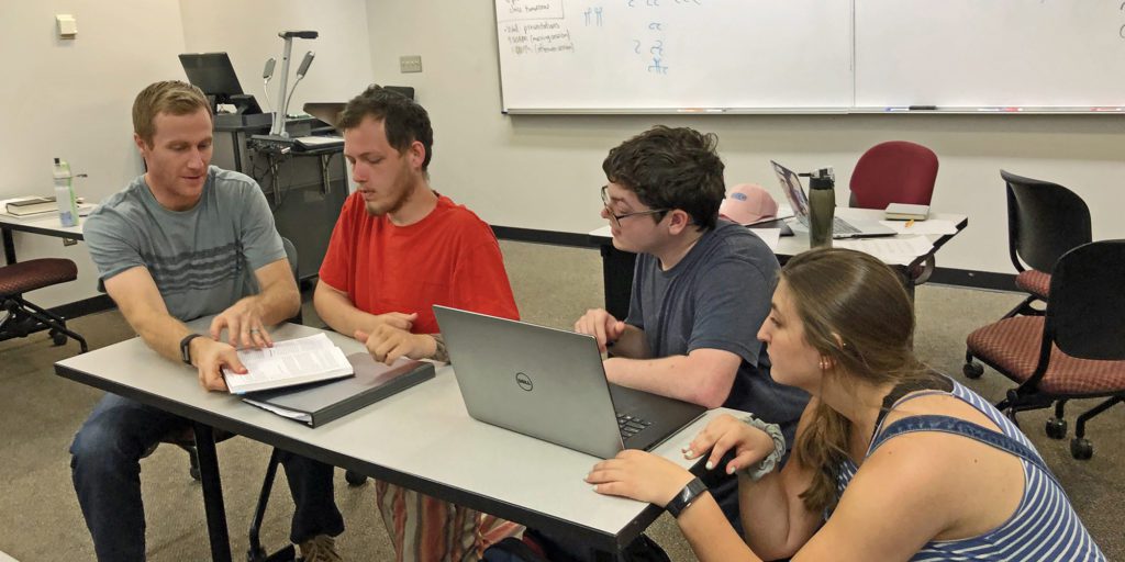 Students working with professor in class