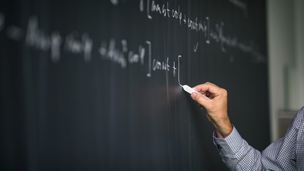 professor writing on blackboard