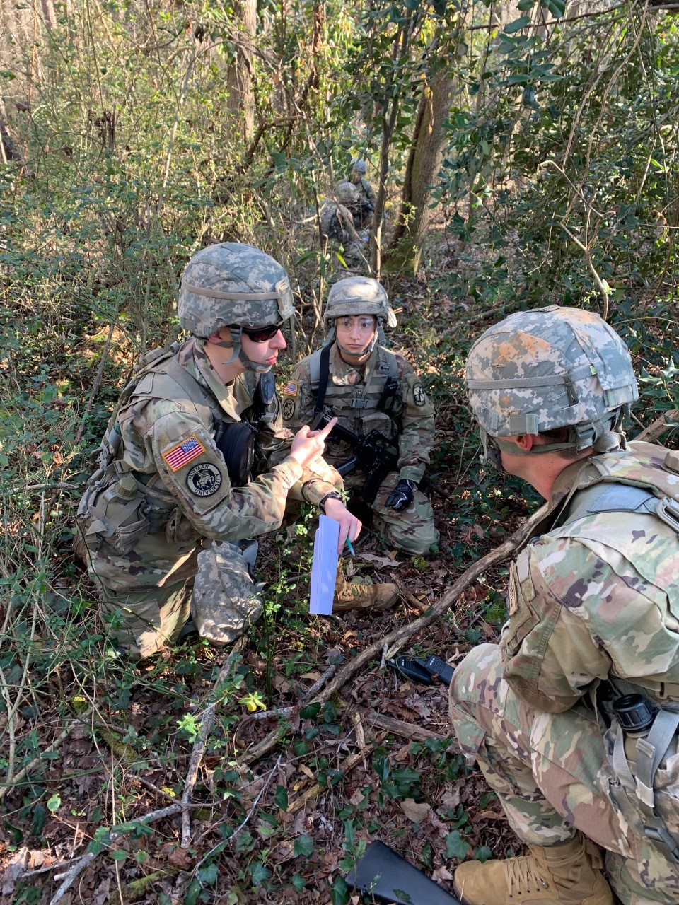 Students squatting in the woods, military dress on
