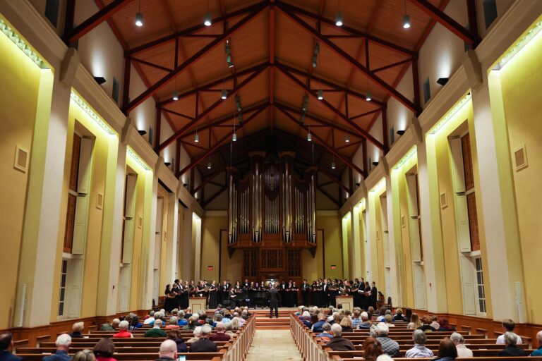 Wide angle photo of Furman Singers performing in Daniel Memorial Chapel in March, 2023. The high church ceiling and audience are visible in the shot.