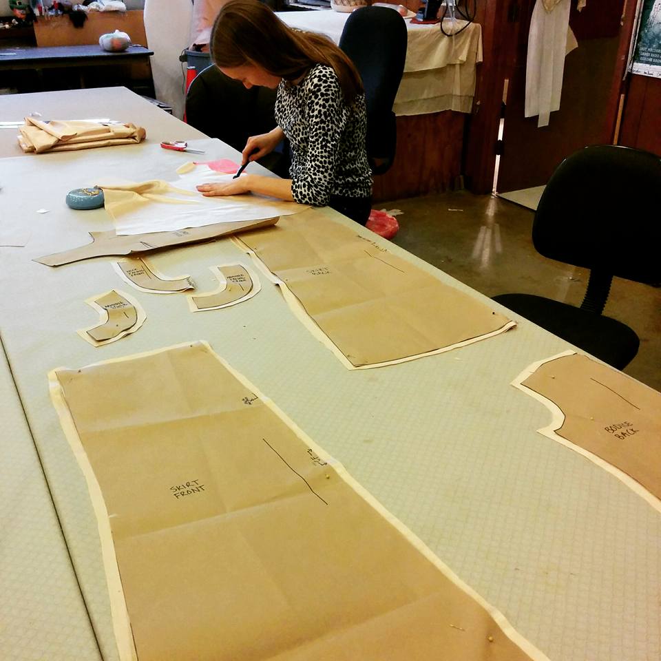 student (Erin Barnett) cutting patterns in costume shop