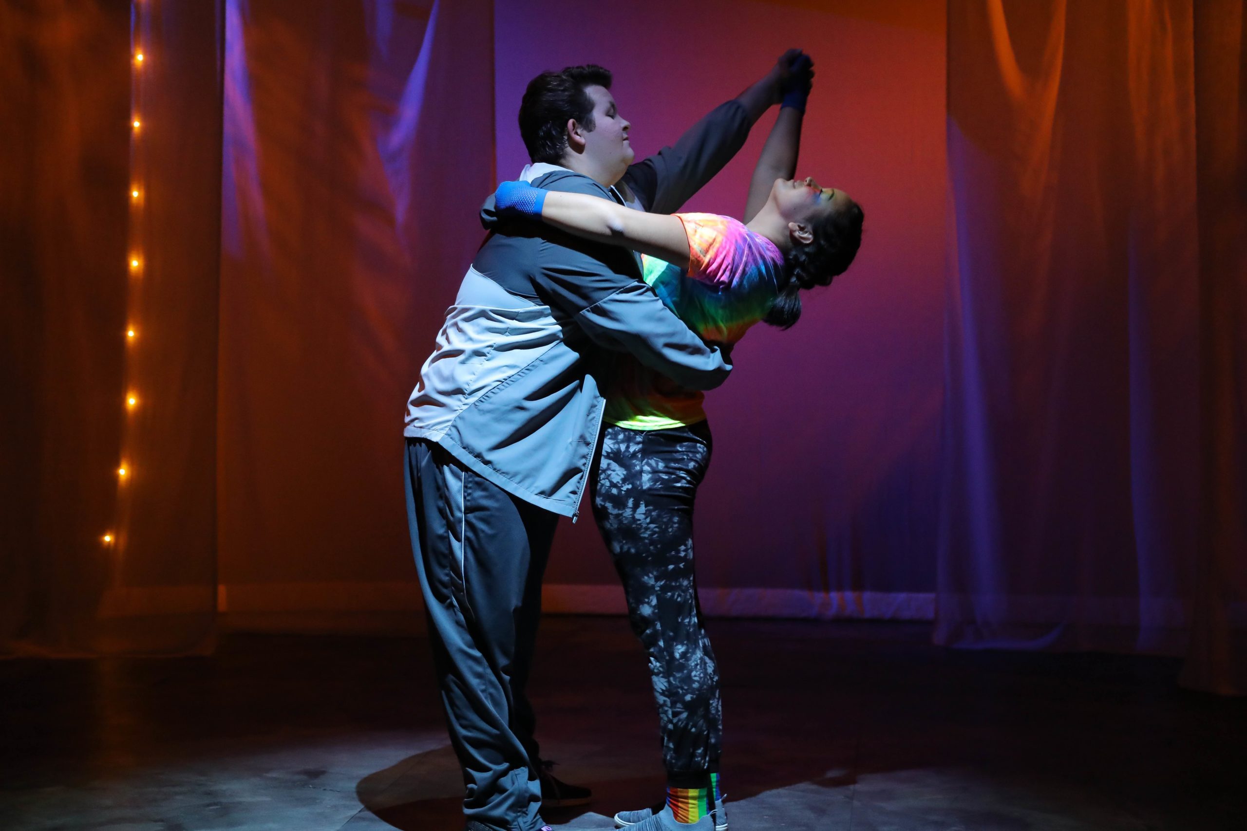 Couple dancing in front of red lighted backdrop