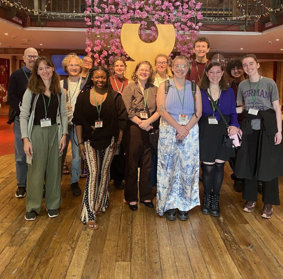 Students stand together in front of the RSC logo at the Royal Shakespeare Company's theatre in Stratford-upon-Avon.