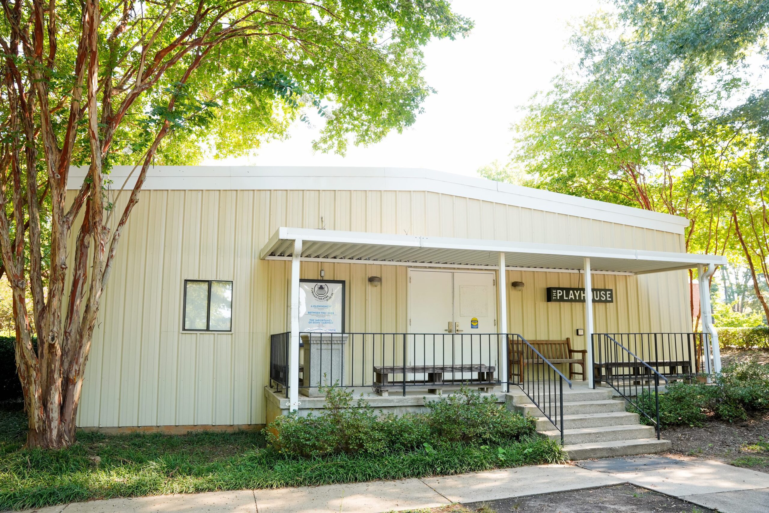 photograph of the front of The Playhouse a tan building with white porch