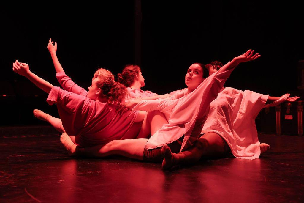 Students seated in a circle in red lighting reaching
