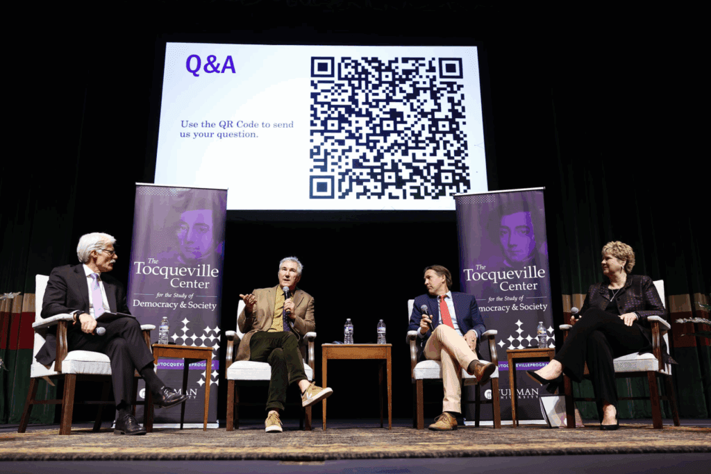 A panel of four speakers seated on stage at the Tocqueville Homecoming event. Brent Nelsen, Elizabeth Davis, John Tomasi, and Ben Sasse. They are seated with microphones, engaged in discussion in front of an audience, with a Tocqueville Program backdrop behind them.