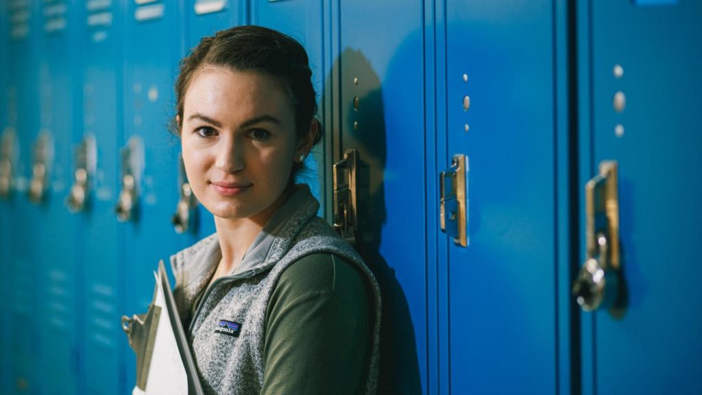 Student with clipboard leaning against locker