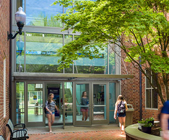 students walking in and out of a building with a glass entrance