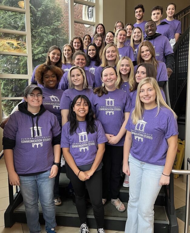 Group of Furman Students in purple t-shirts posing on staircase inside Furman Hall.