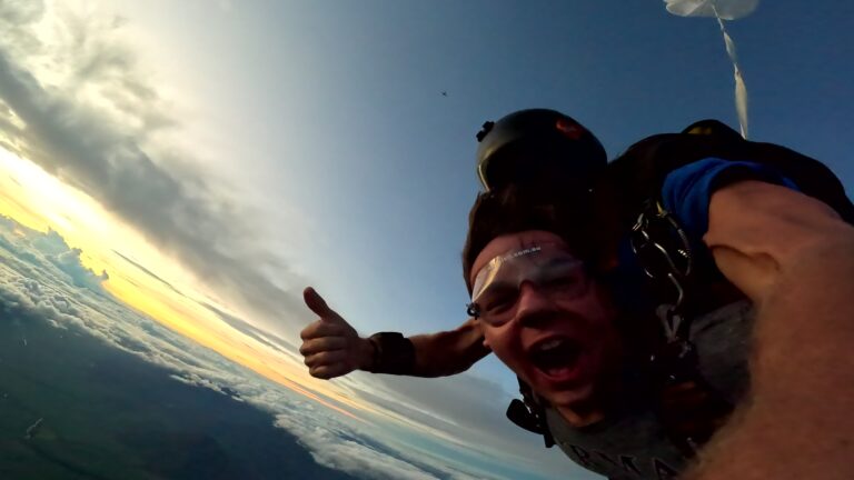Two people skydiving in tandem. Supervisor gives a thumbs up as the passenger laughs with excitement.