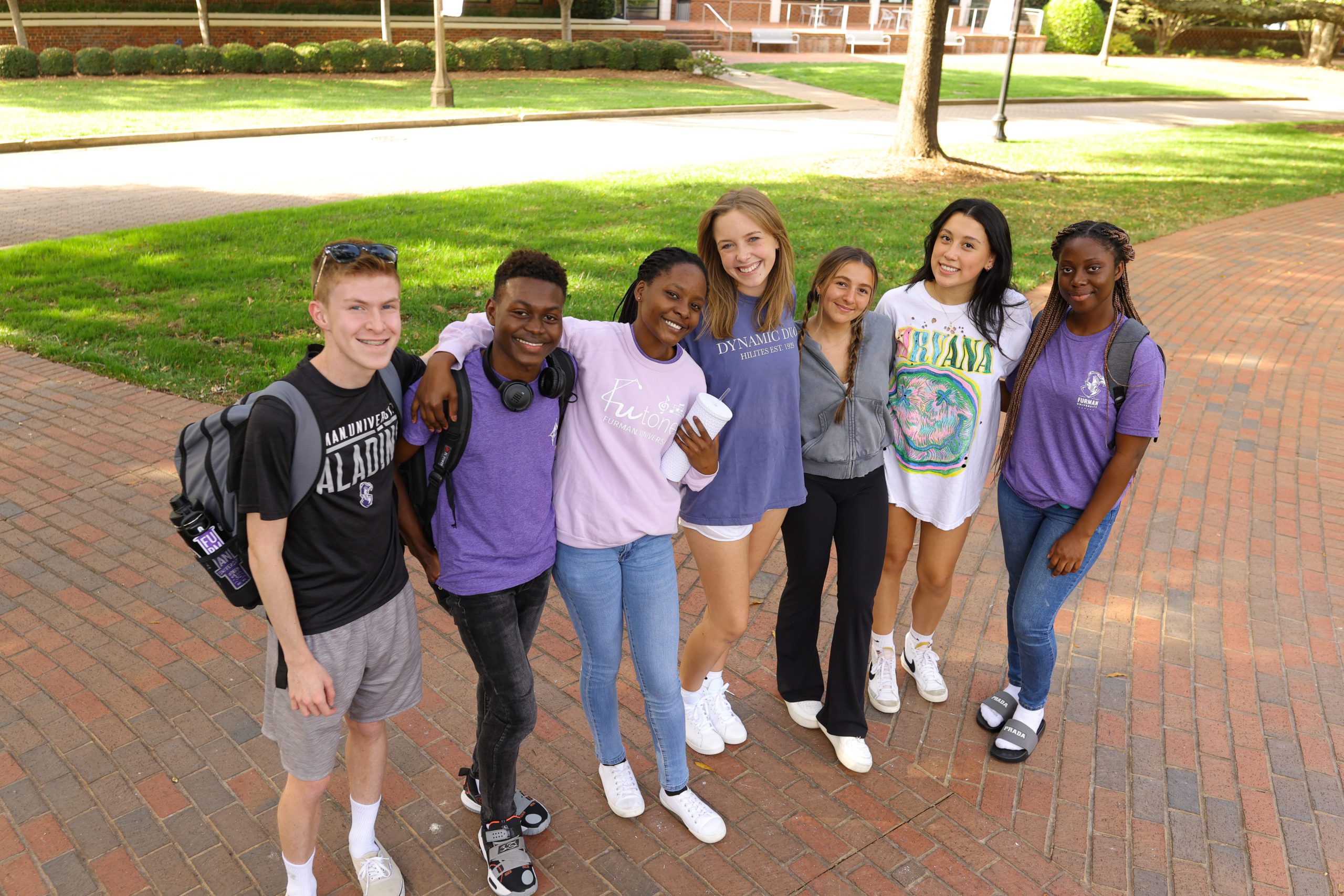 male and female students pose together on campus with their arms around one another