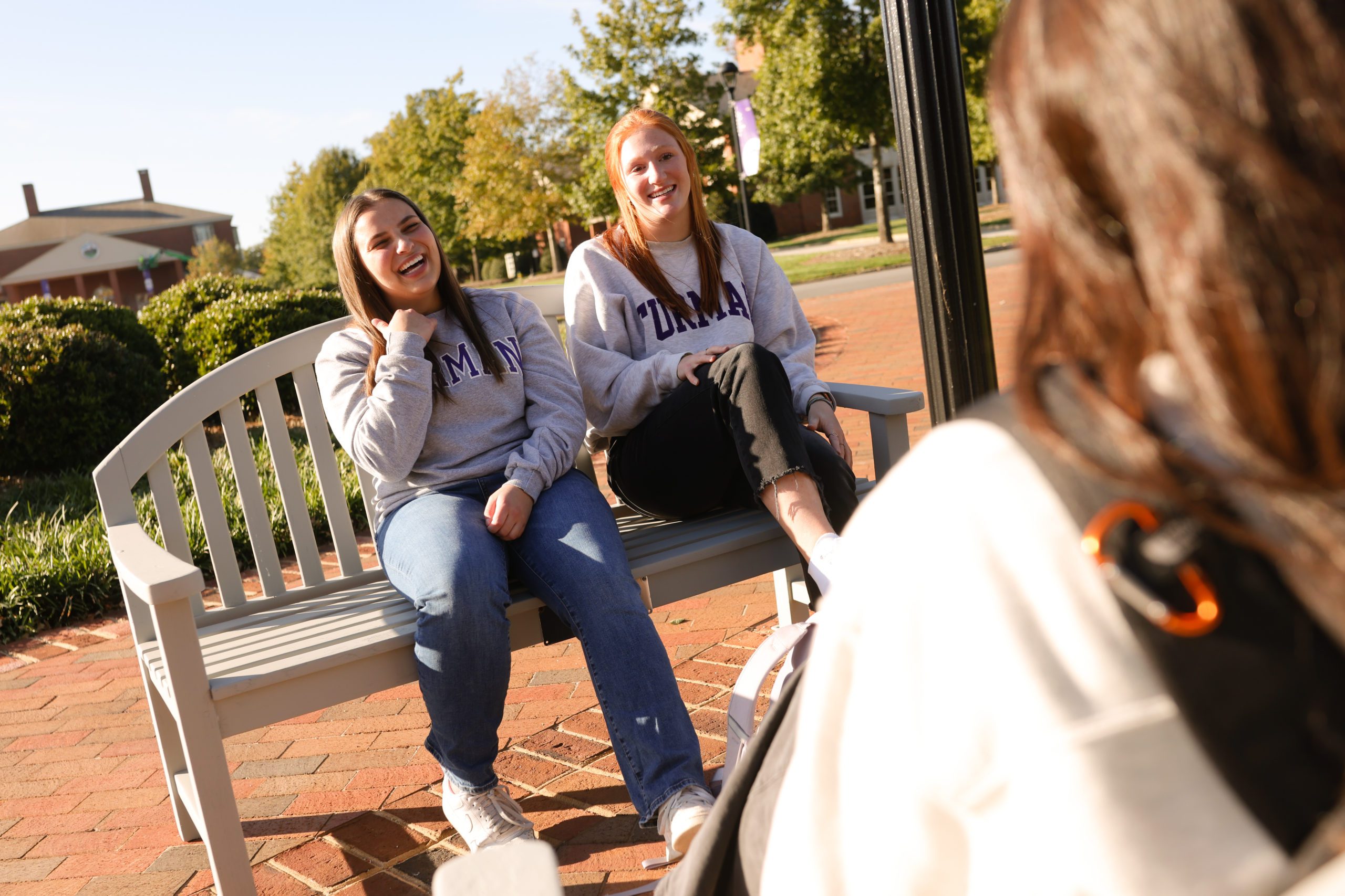 Students sitting and talking on a bench on Furman campus