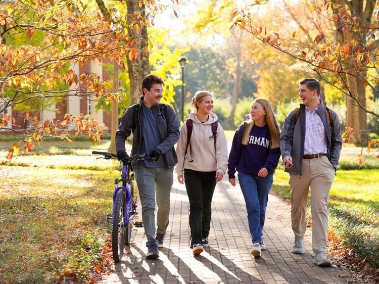 Student walking under autumn trees on campus