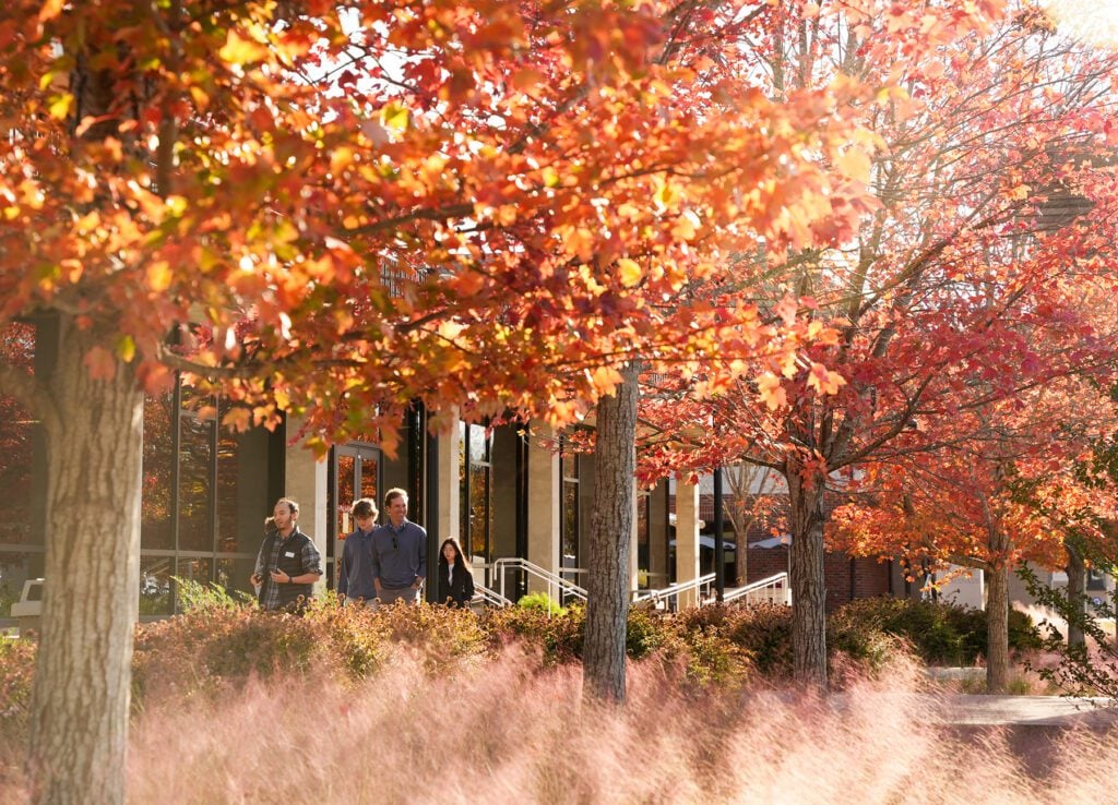 A group walks through campus on a fall day