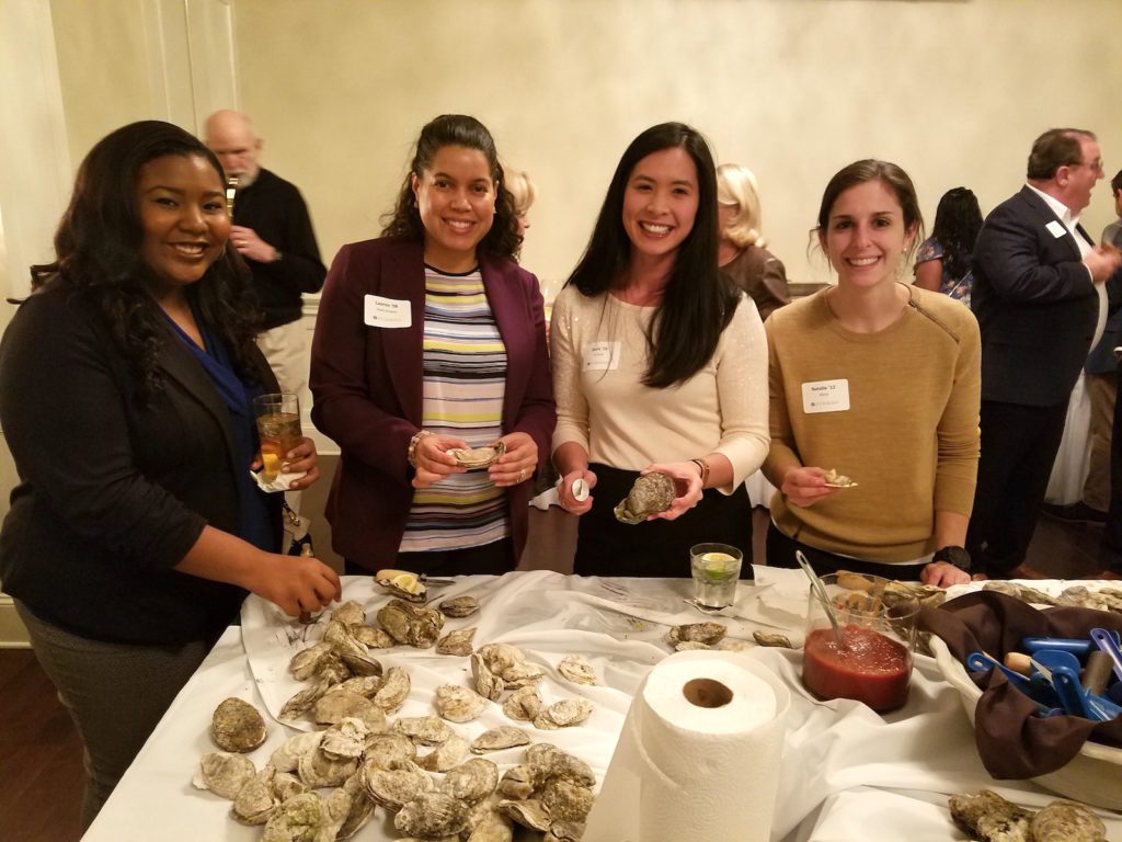 Alumni holding oysters at Fan Club event