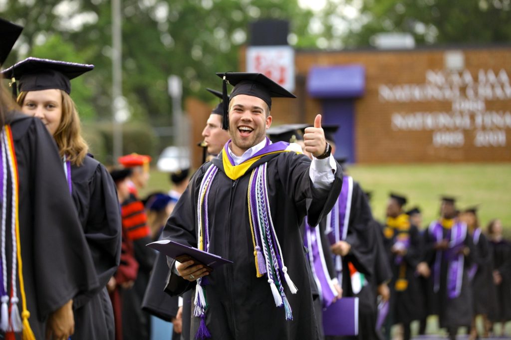 Graduate giving a thumbs up during commencement