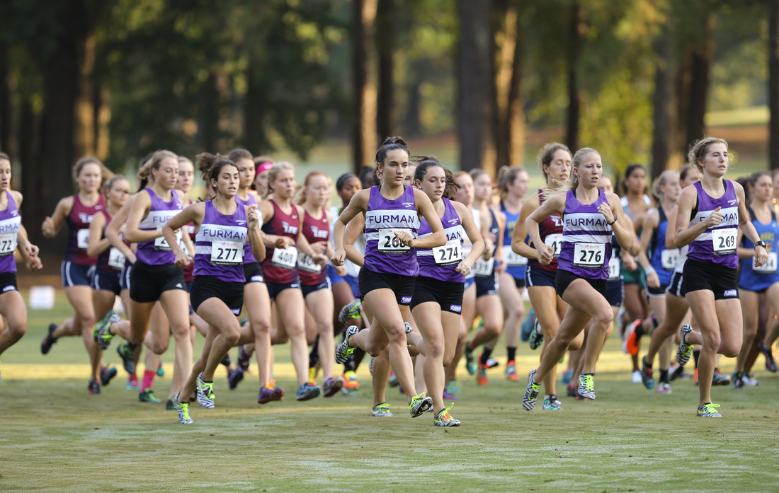 Girls cross country members running across a field