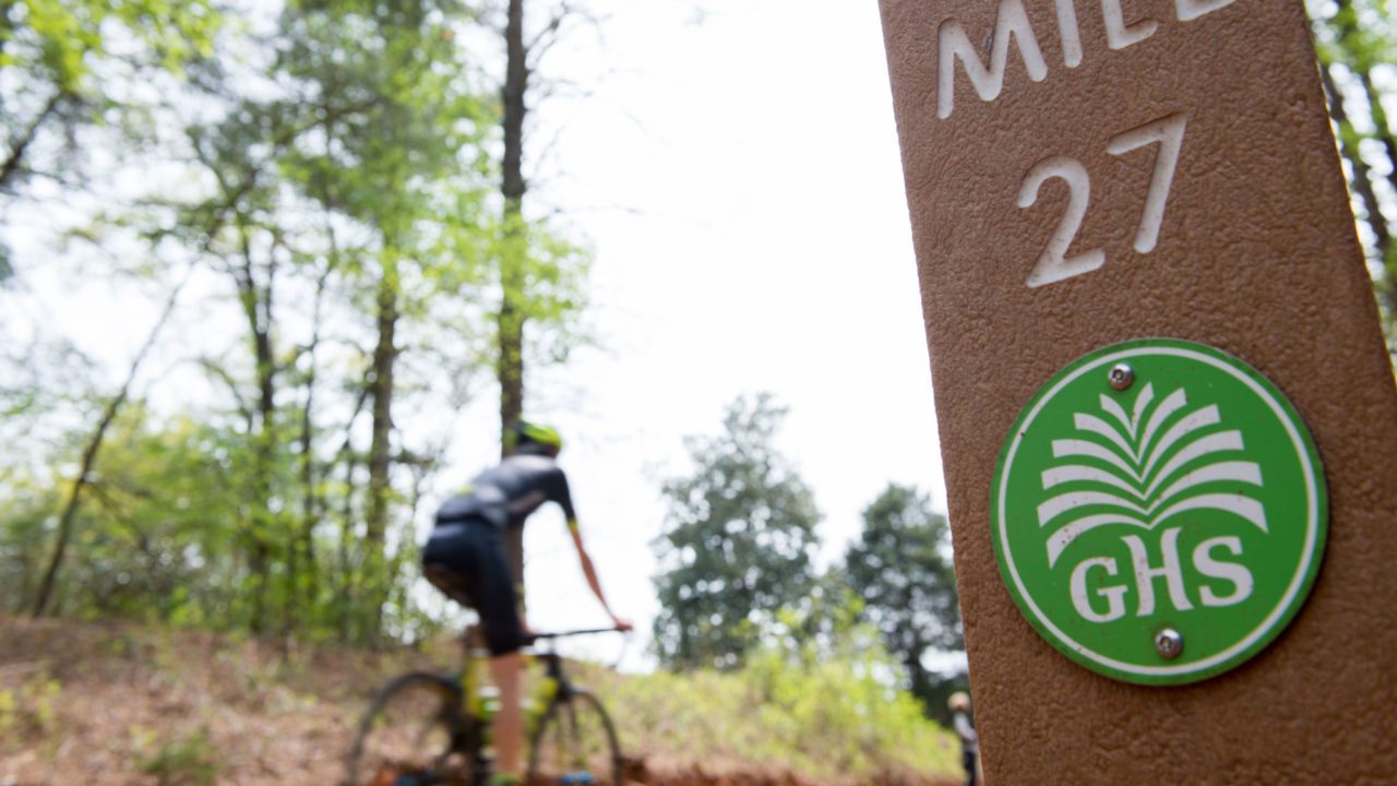 Mile marker on Swamp Rabbit trail, man on bike in background