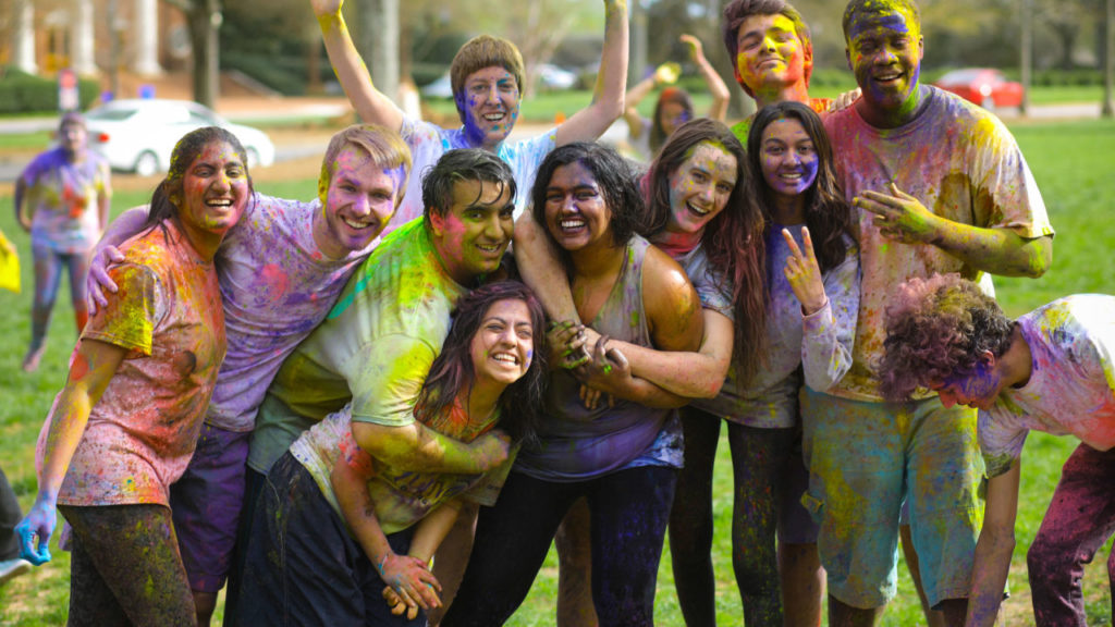 Students smiling, covered in splotches of paint from Holi festival