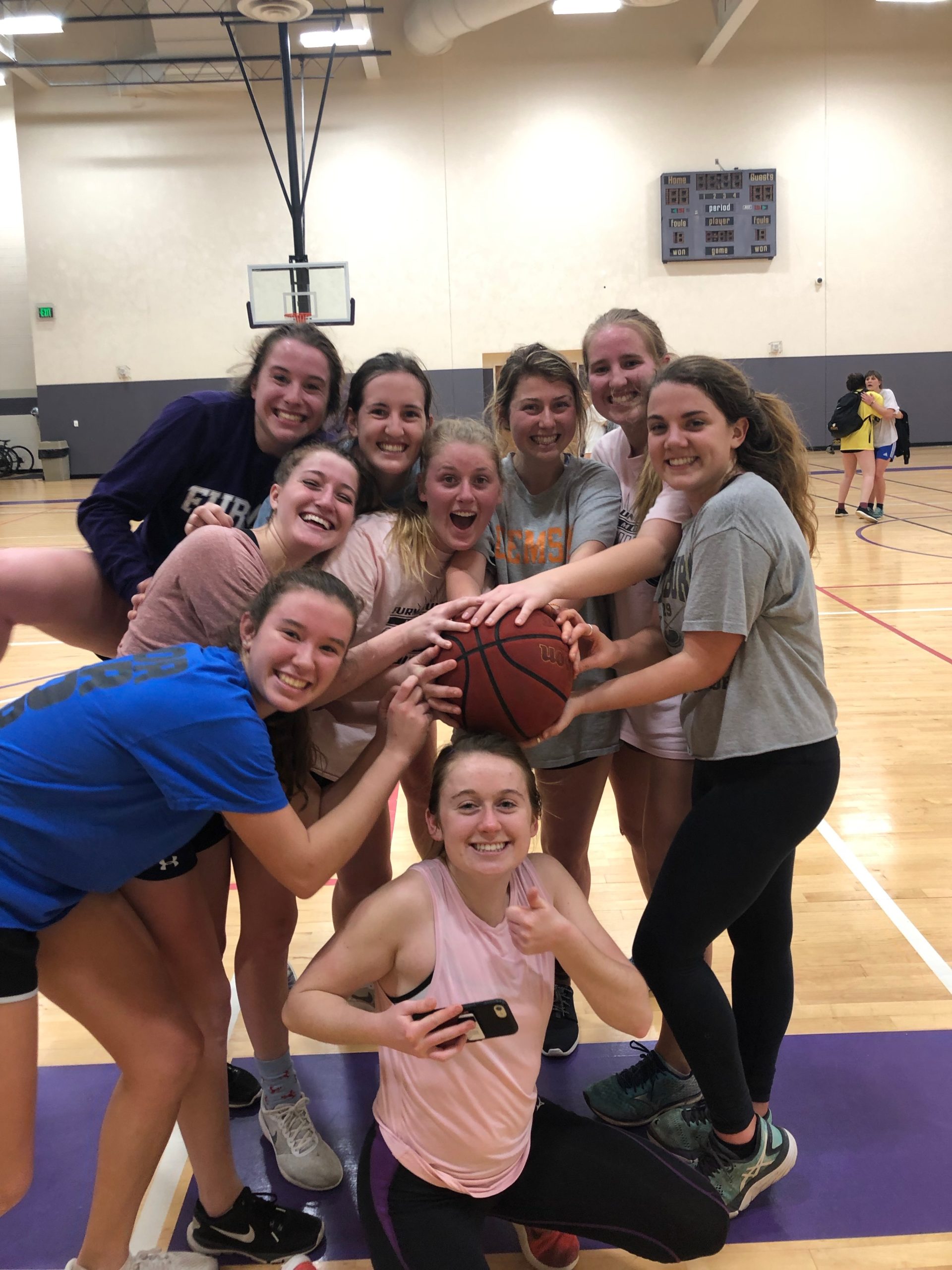 Students smiling in group shot, holding basketball