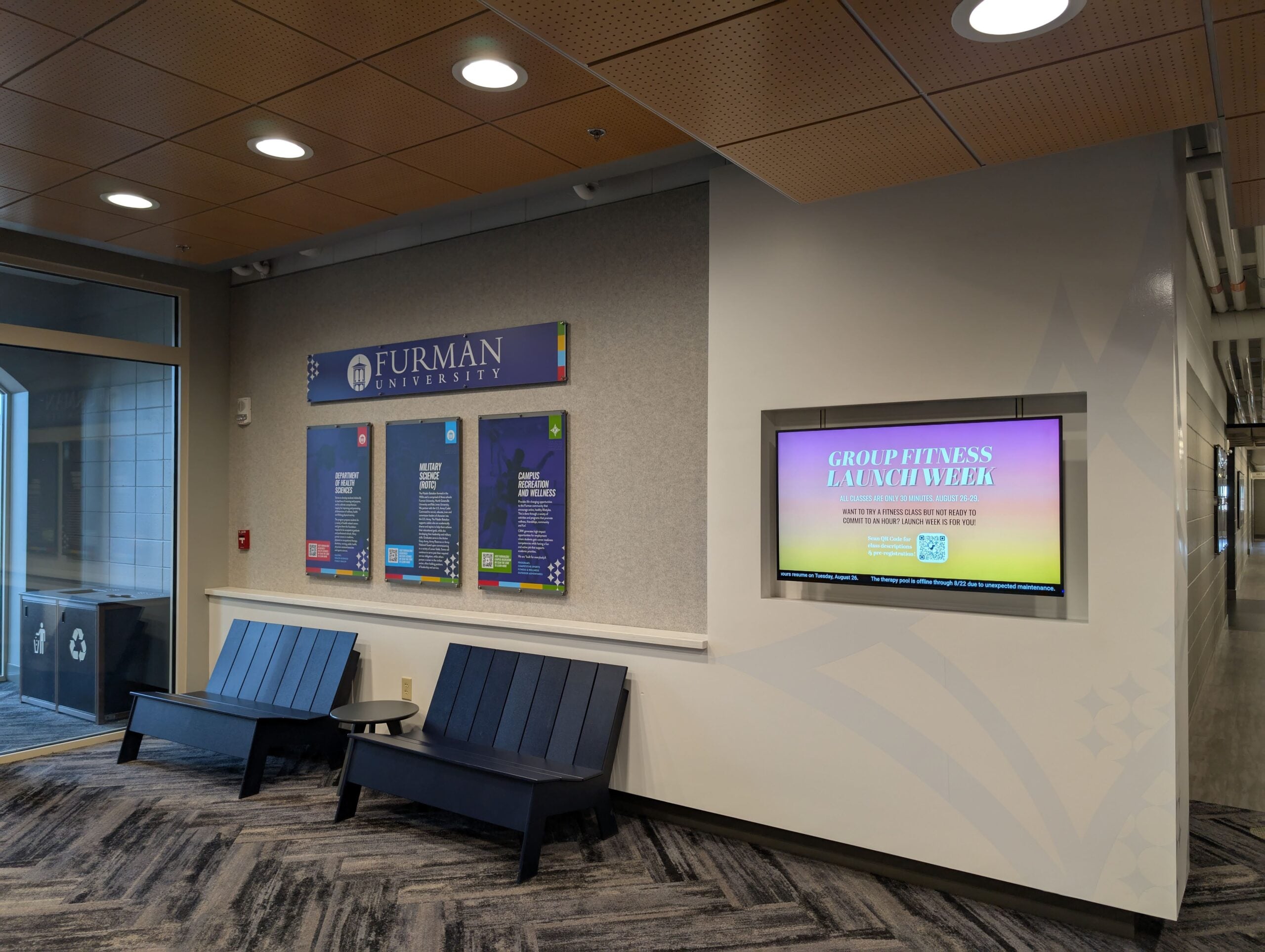 Lobby entrance shows digital display board and furniture