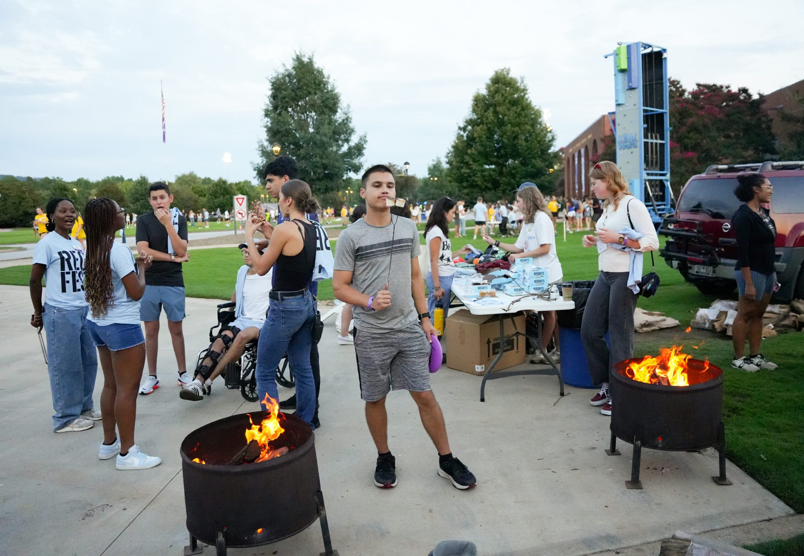 A student inspects their toasted marshmallow surrounded by other students engaging.