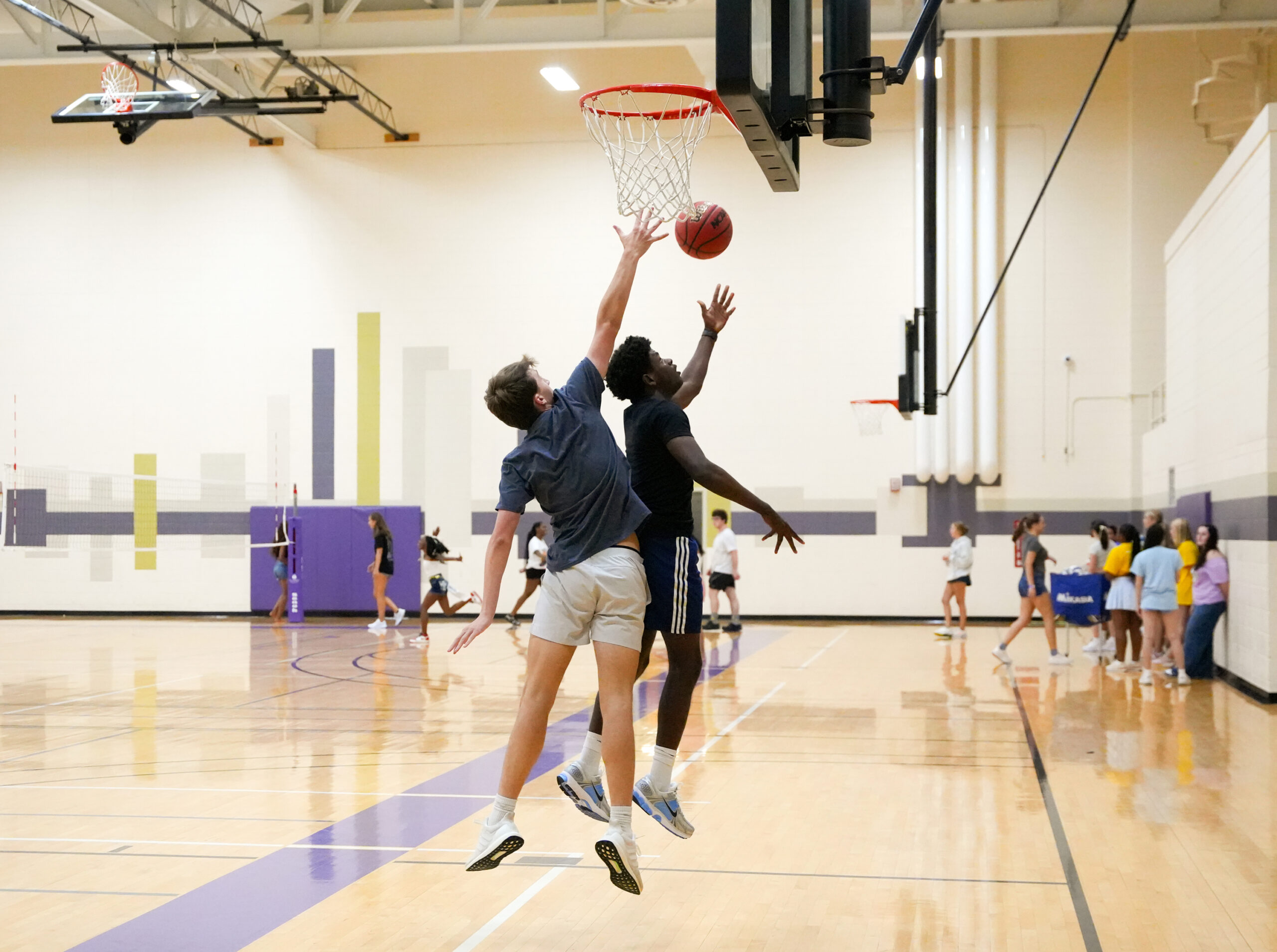 Two students jump for a basketball with their feet floating off the ground.