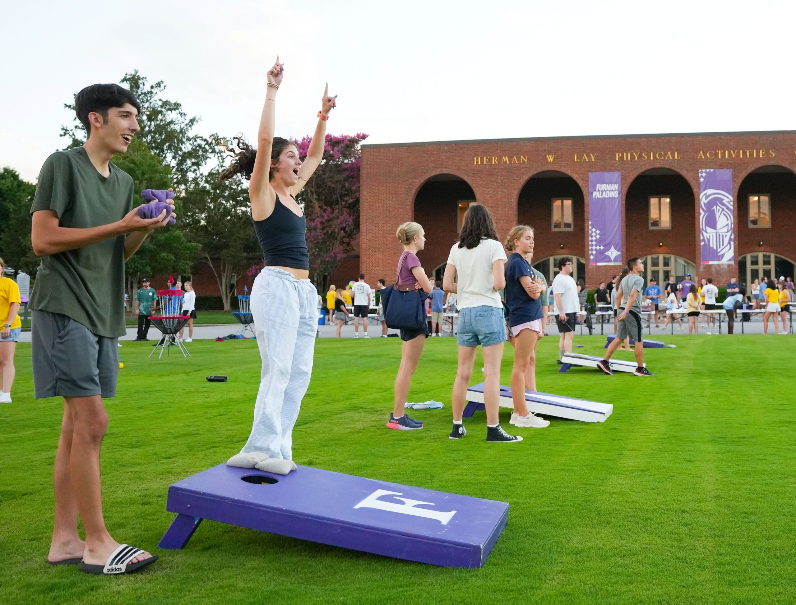 Students scattered across the PAC circle playing yard games with a student celebrating a good toss in the foreground.
