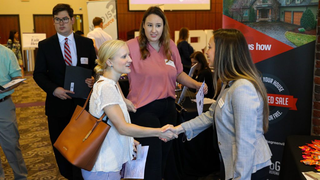 Student shaking hands with representatives of a corporation