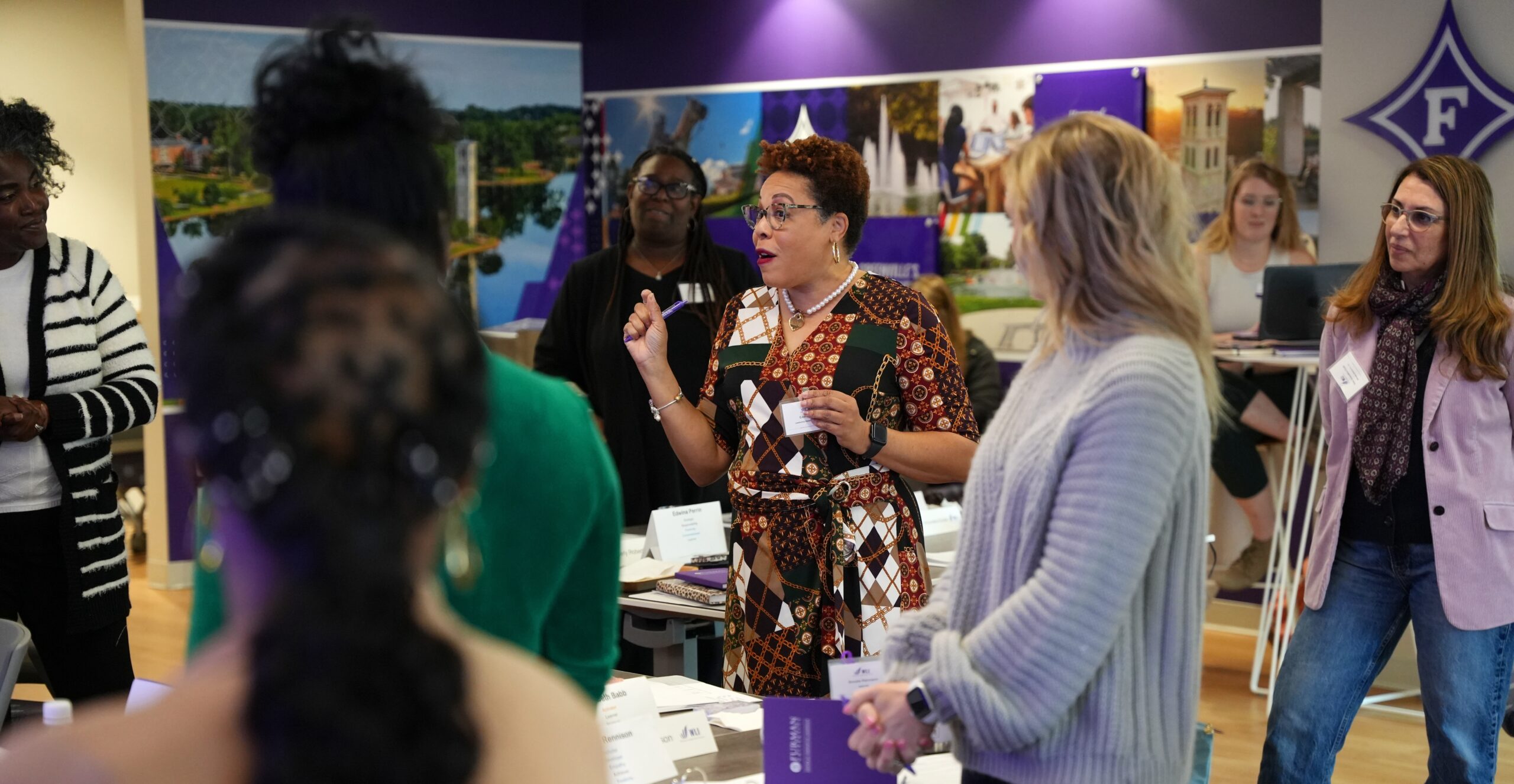 A group of diverse women standing are listening to one speaking