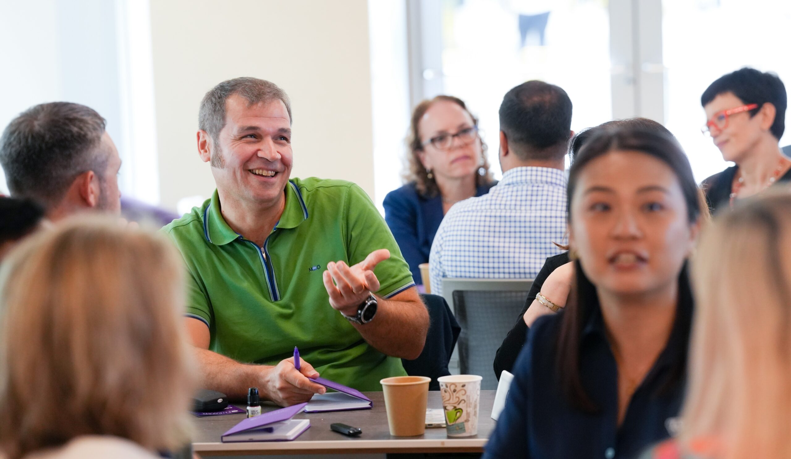 a group of diverse people are talking at a table