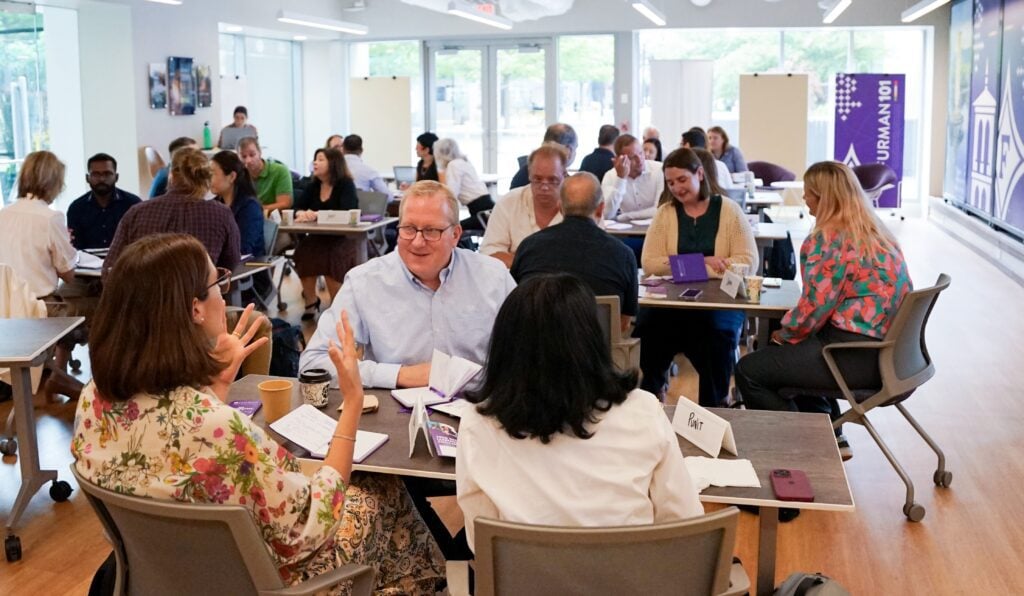 A full room of diverse individuals from a single organization and actively participating in a workshop.