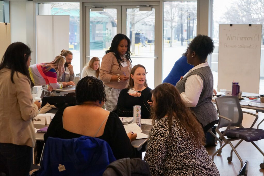 A group of diverse women are actively discussing around a table.