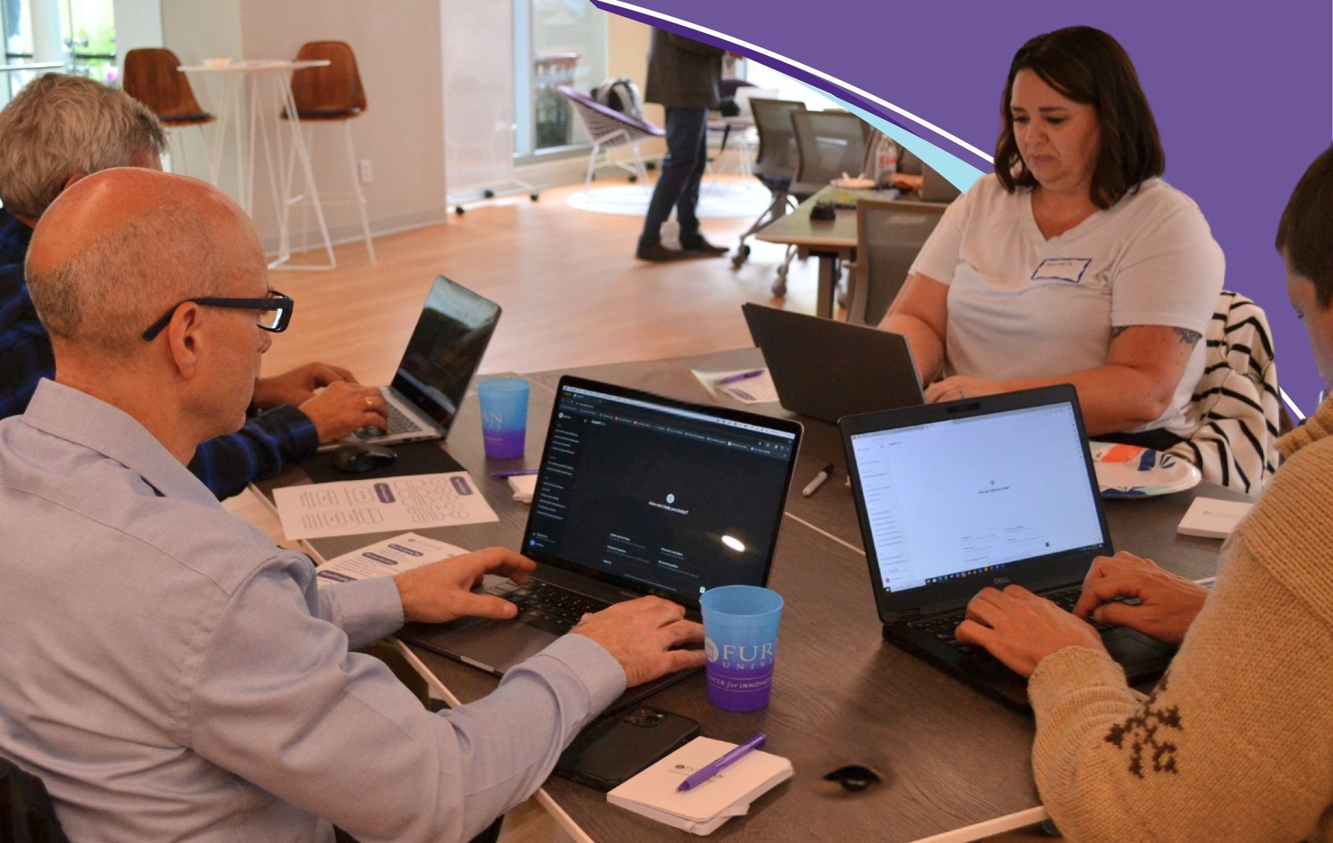 People sitting at table looking at laptops.