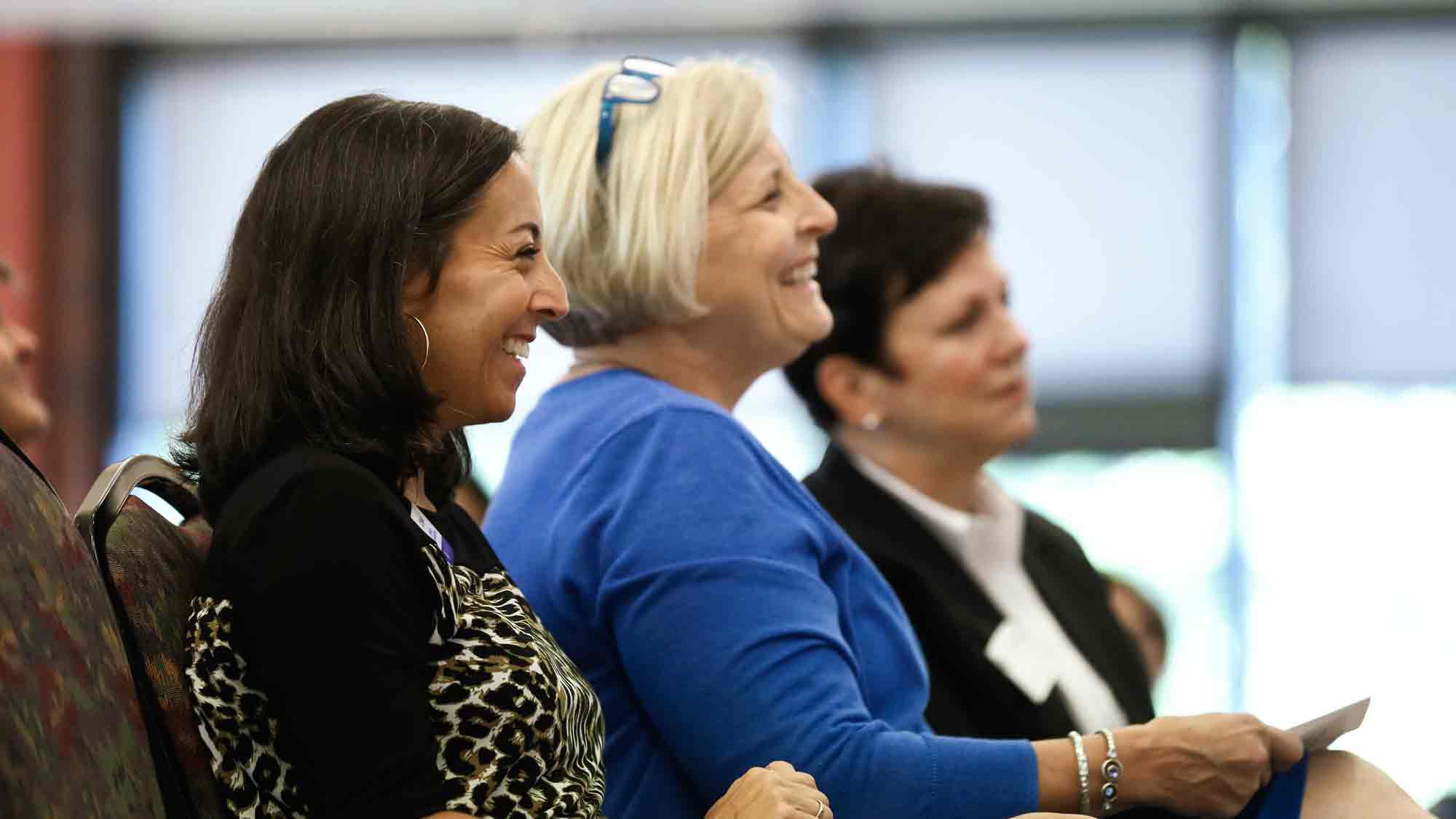Women smiling and listening to speaker