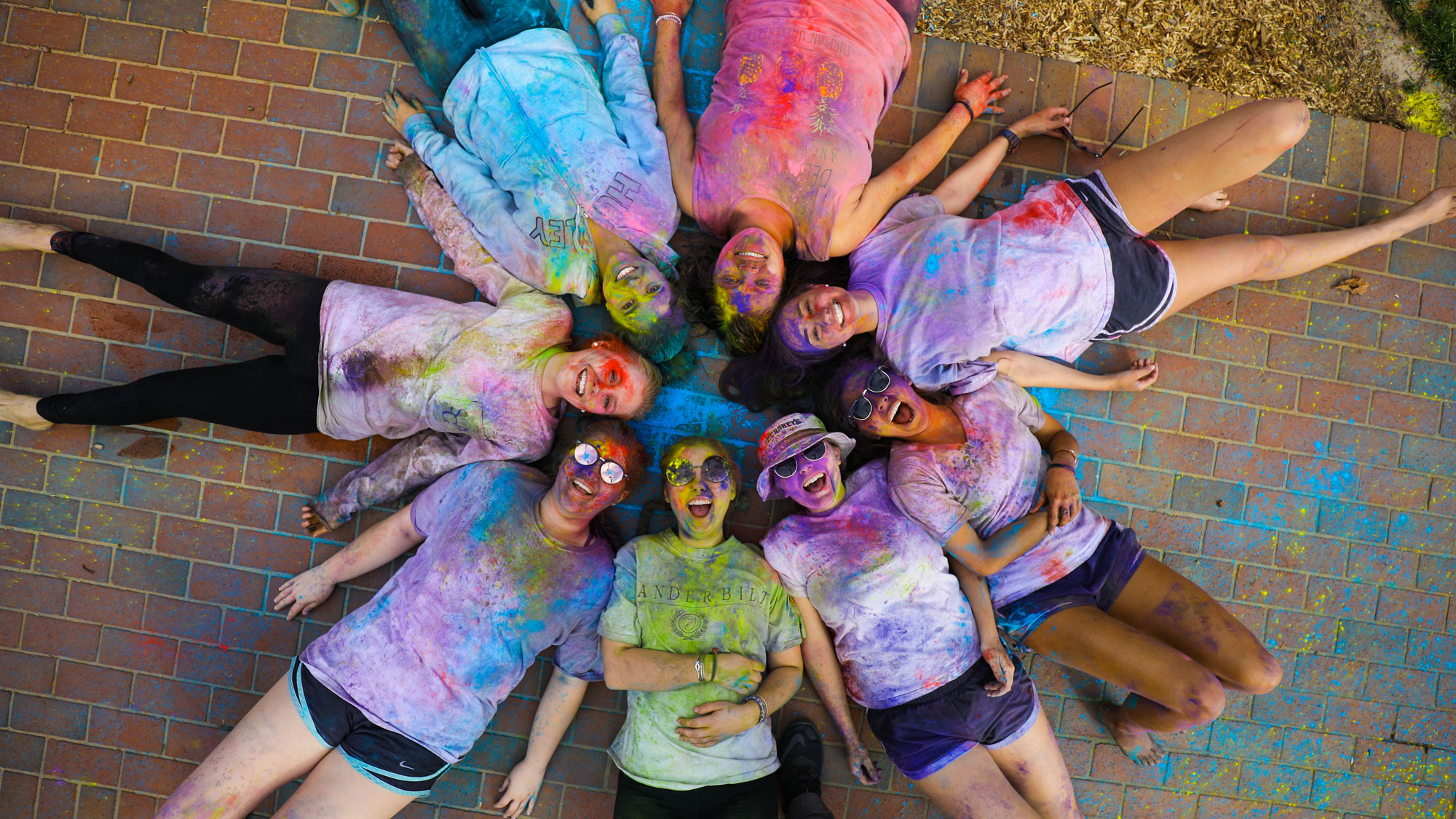 Students covered in splotches of paint and smiling, having just participated in the Holi festival