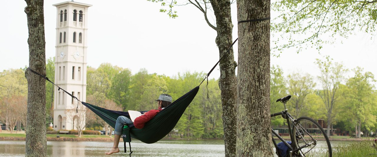 Student sitting in hammock across from the bell tower