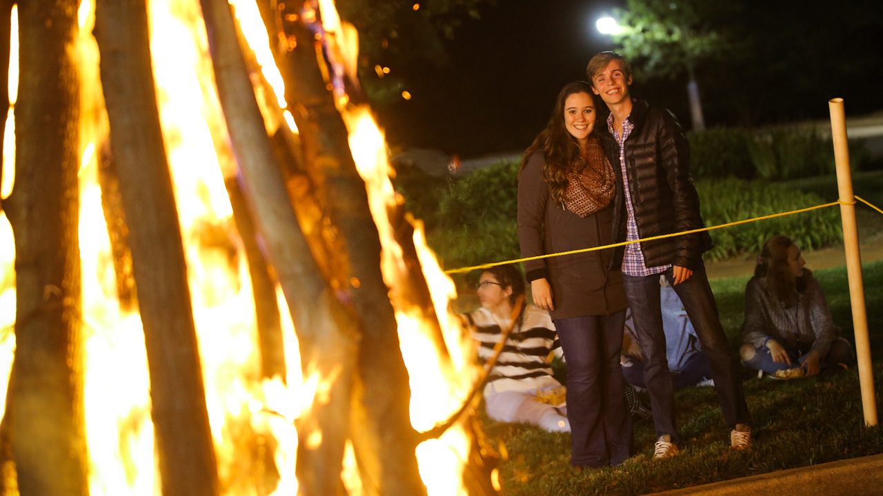 Students outside around bonfire during homecoming