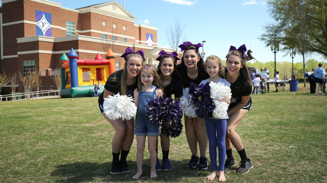 Student cheerleaders with girls at summer camp