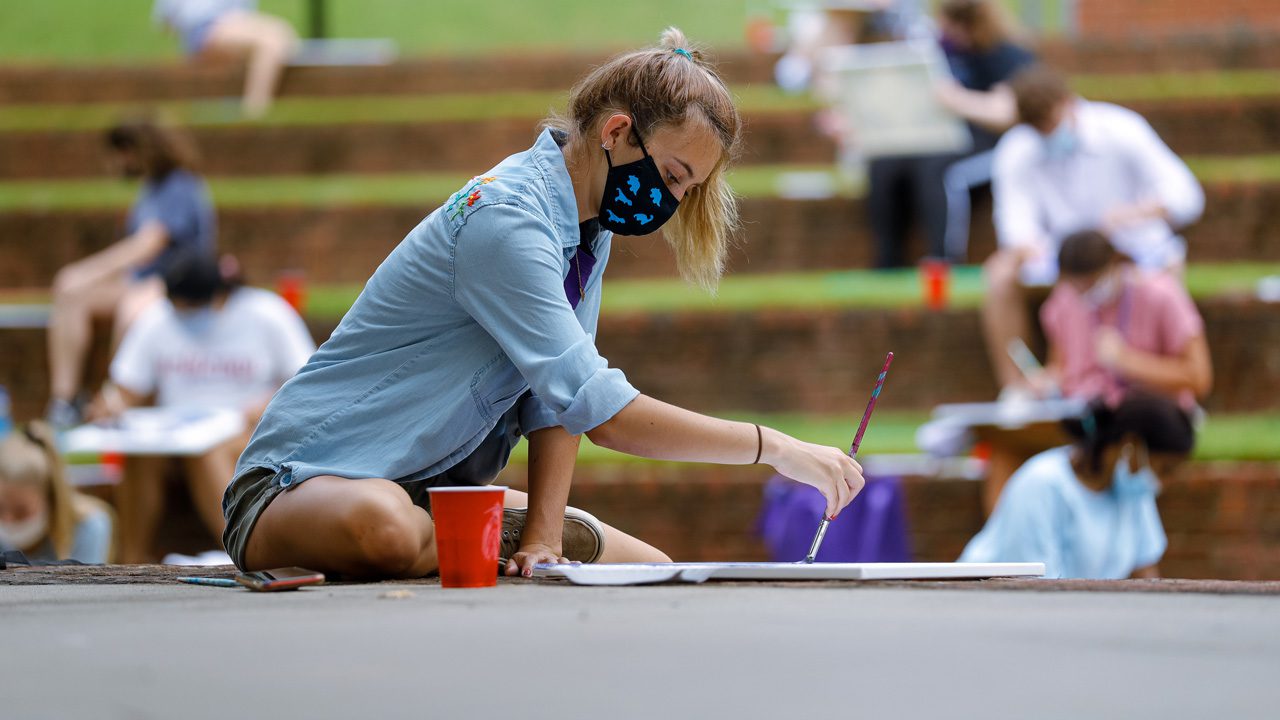 Student painting outside during an art class
