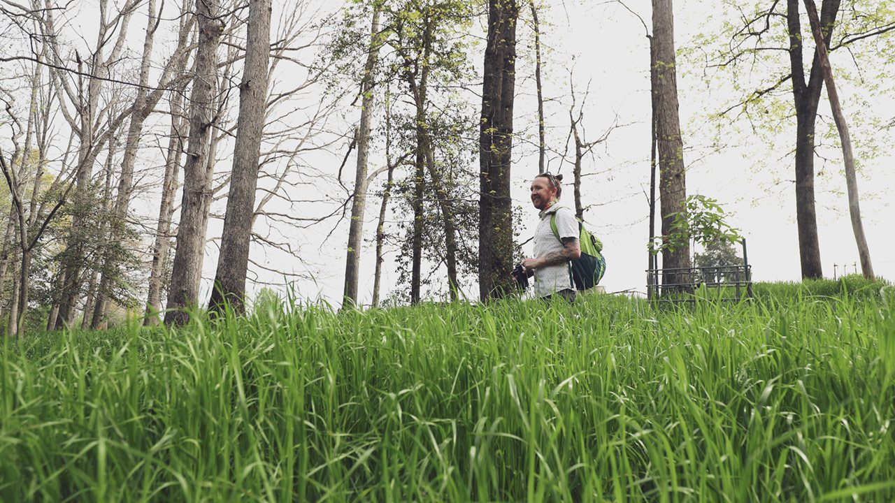 John Quinn standing in tall grass with binoculars