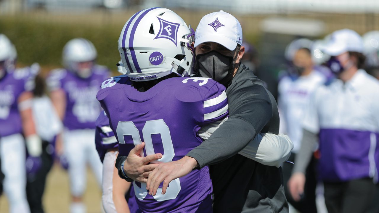 A Furman football player embraces a coach